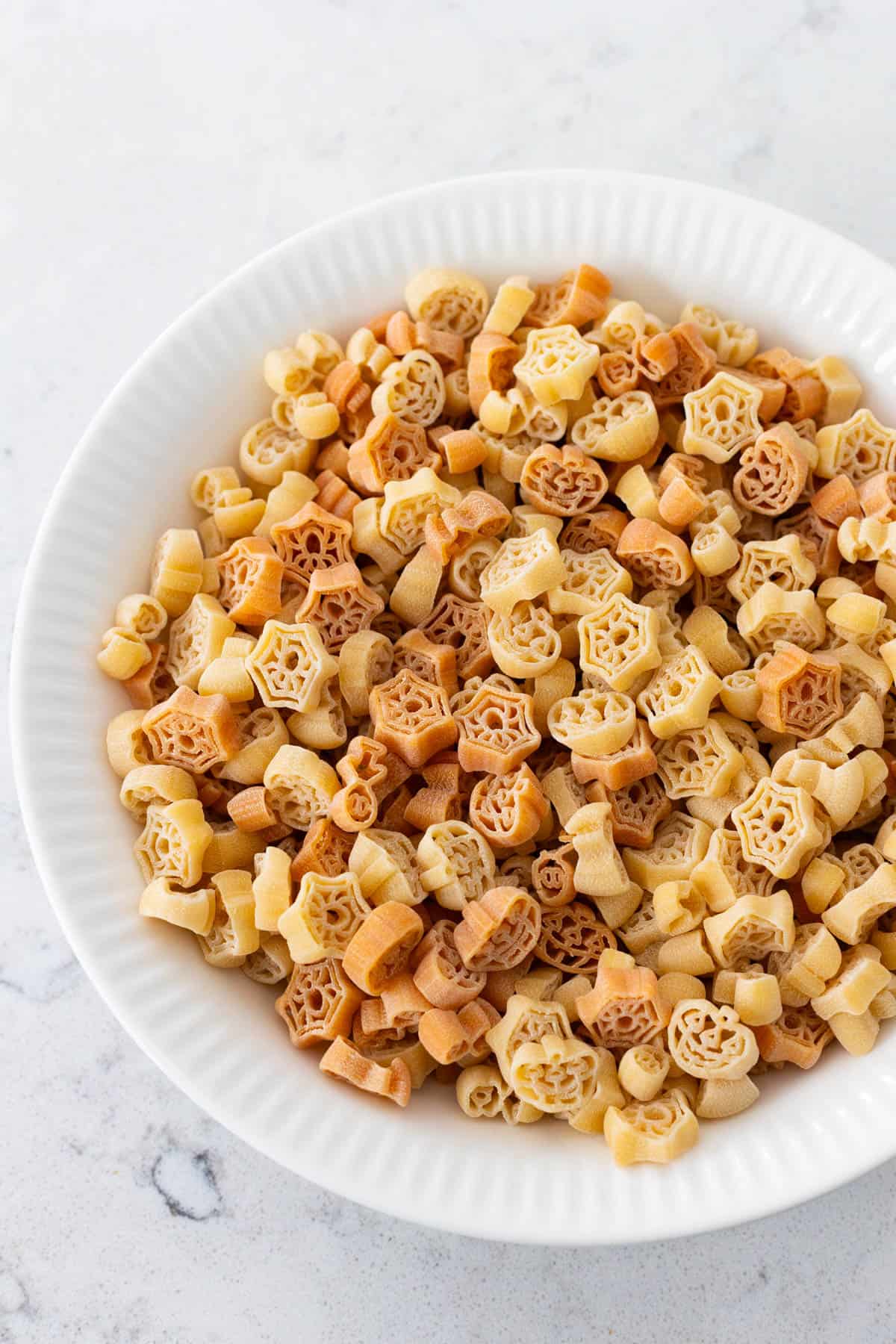 The dried Halloween pasta has been poured into a bowl to show off a closer look at the shapes and colors of the party pasta.