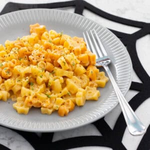 A grey plate has Halloween pasta scooped on top, the plate rests on a spiderweb place mat.