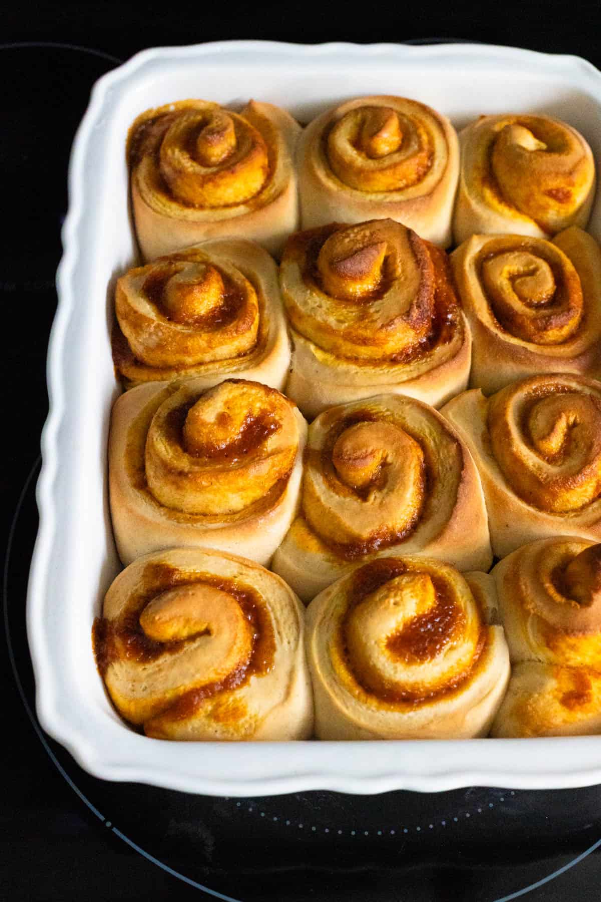 Baking dish filled with golden brown cinnamon rolls fresh from the oven.