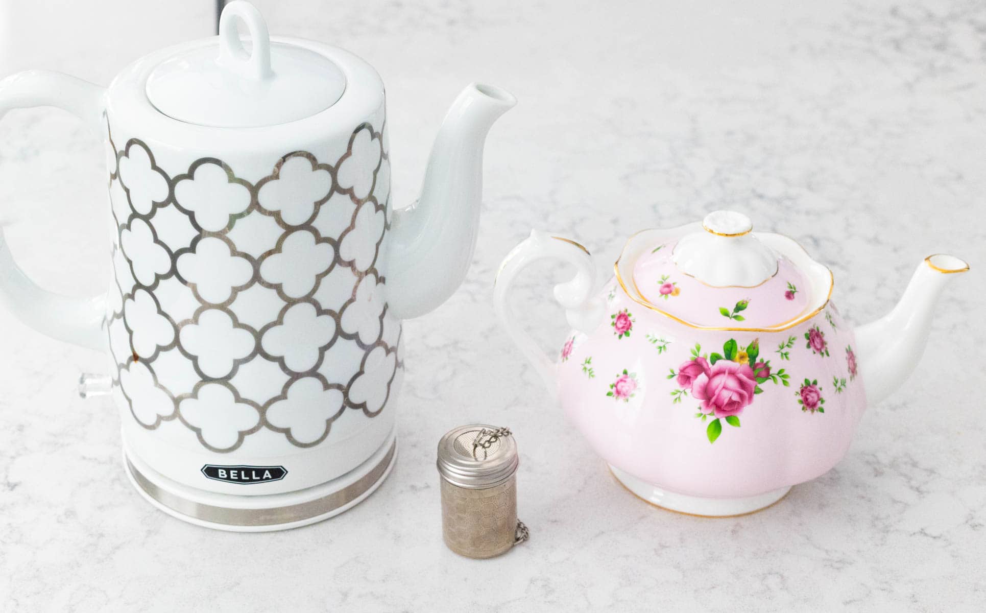 A tea kettle, tea pot, and tea strainer are on the kitchen counter.