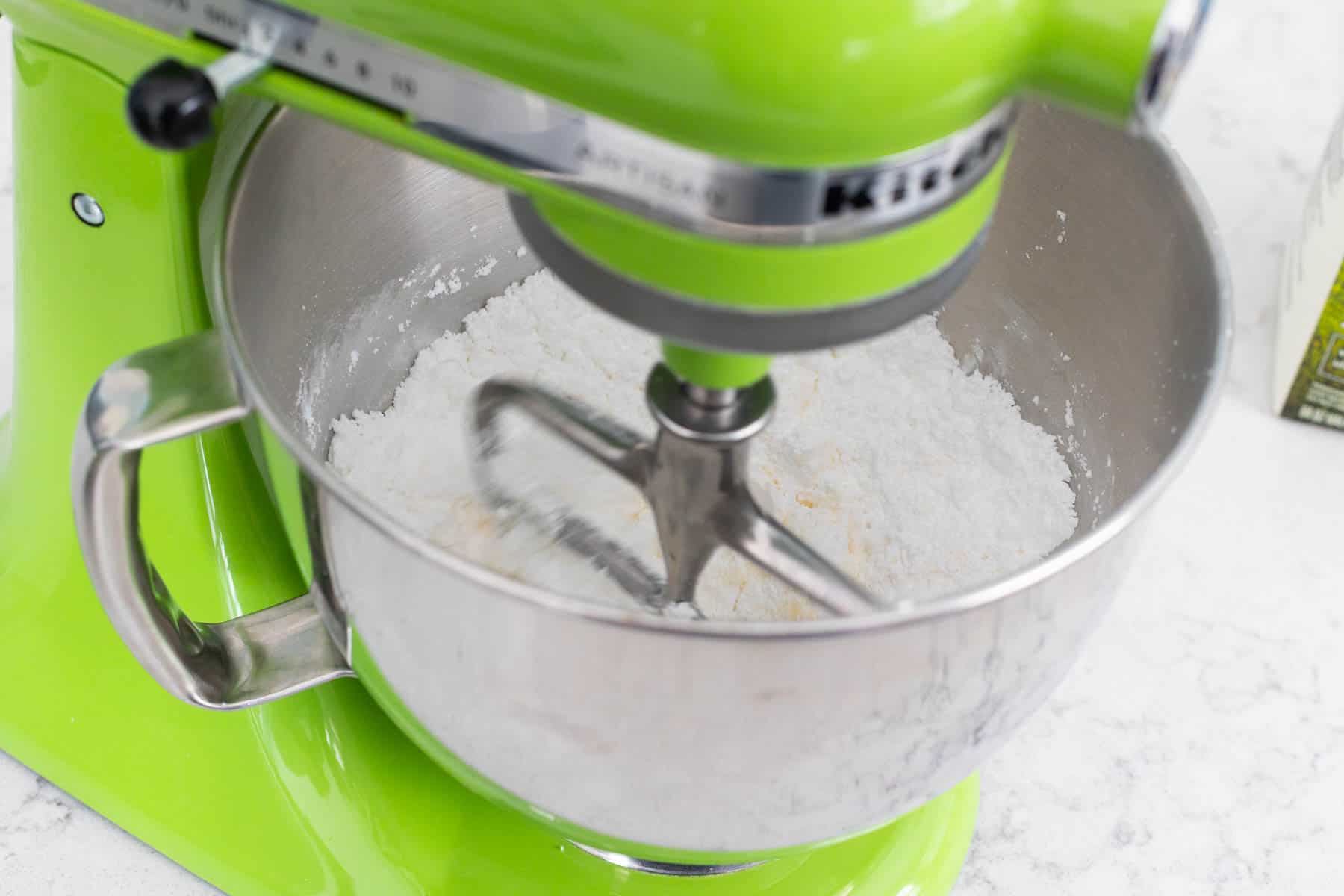 The butter and powdered sugar have been added to the bowl of a stand mixer.