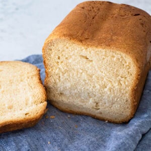 A loaf of white bread that has been baked in a bread maker has been sliced open.