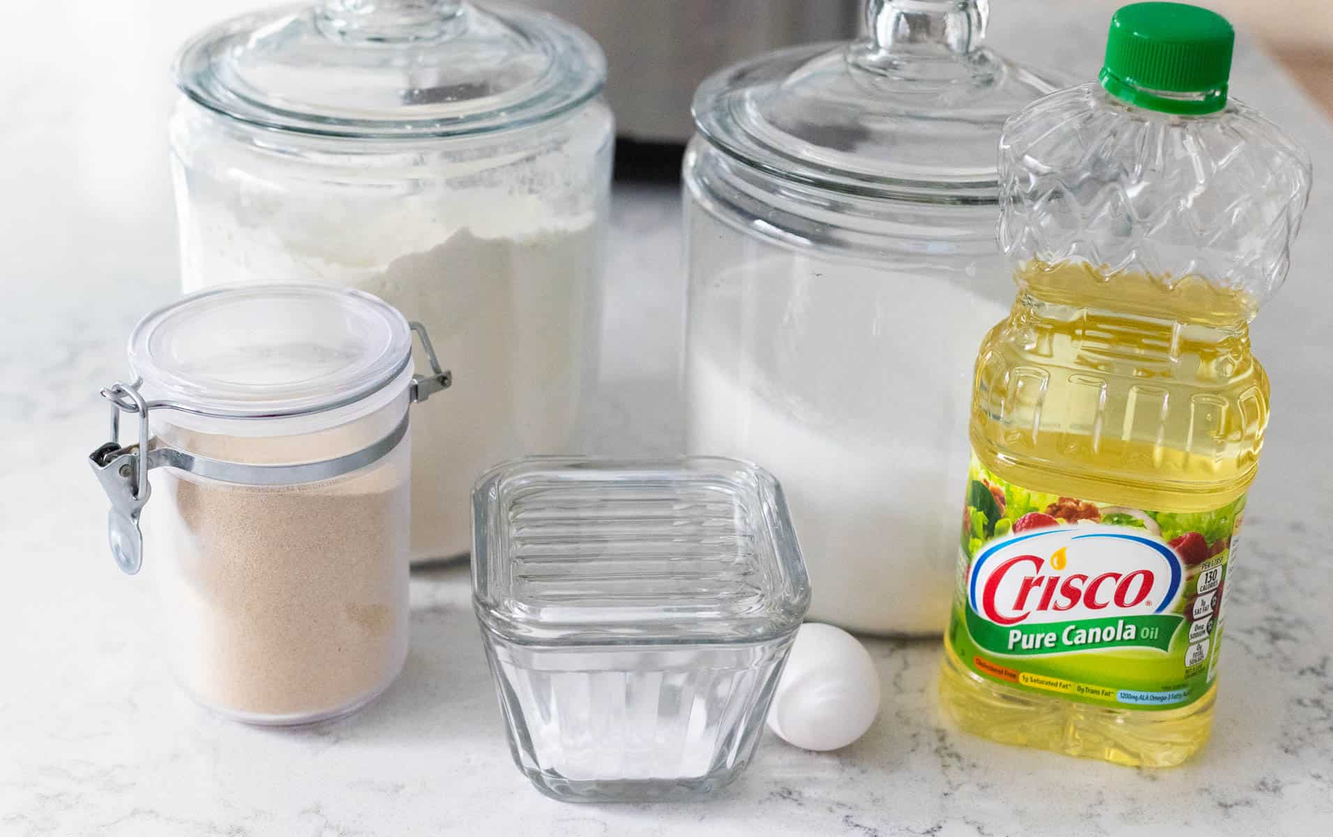 The ingredients to make white bread in a bread machine are on the counter.