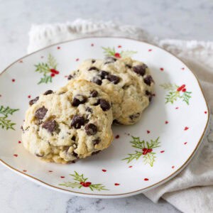 A pair of chocolate chip scones on a Christmas holly plate.