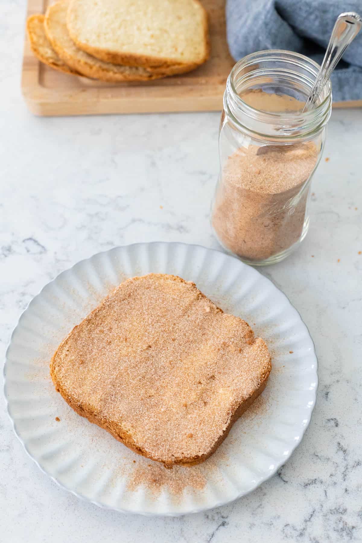 The cinnamon sugar is being spread evenly over the buttered bread.