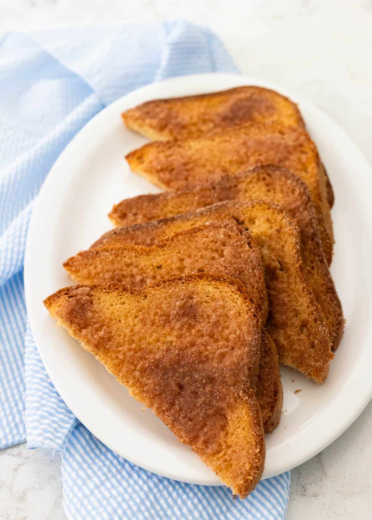 A white platter is filled with cinnamon toast slices.