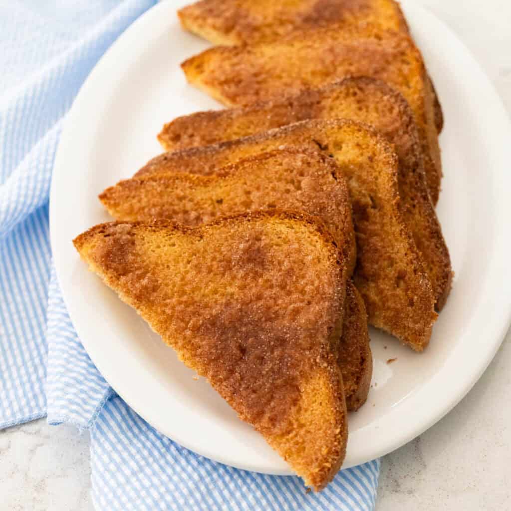 A white platter is filled with cinnamon toast slices.