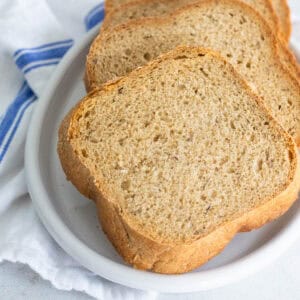 A sliced rye bread is served on a white platter.