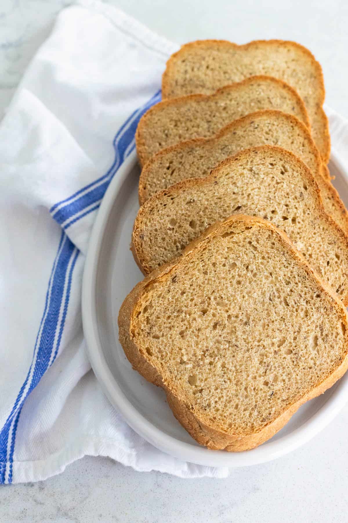 A sliced rye bread is served on a white platter.