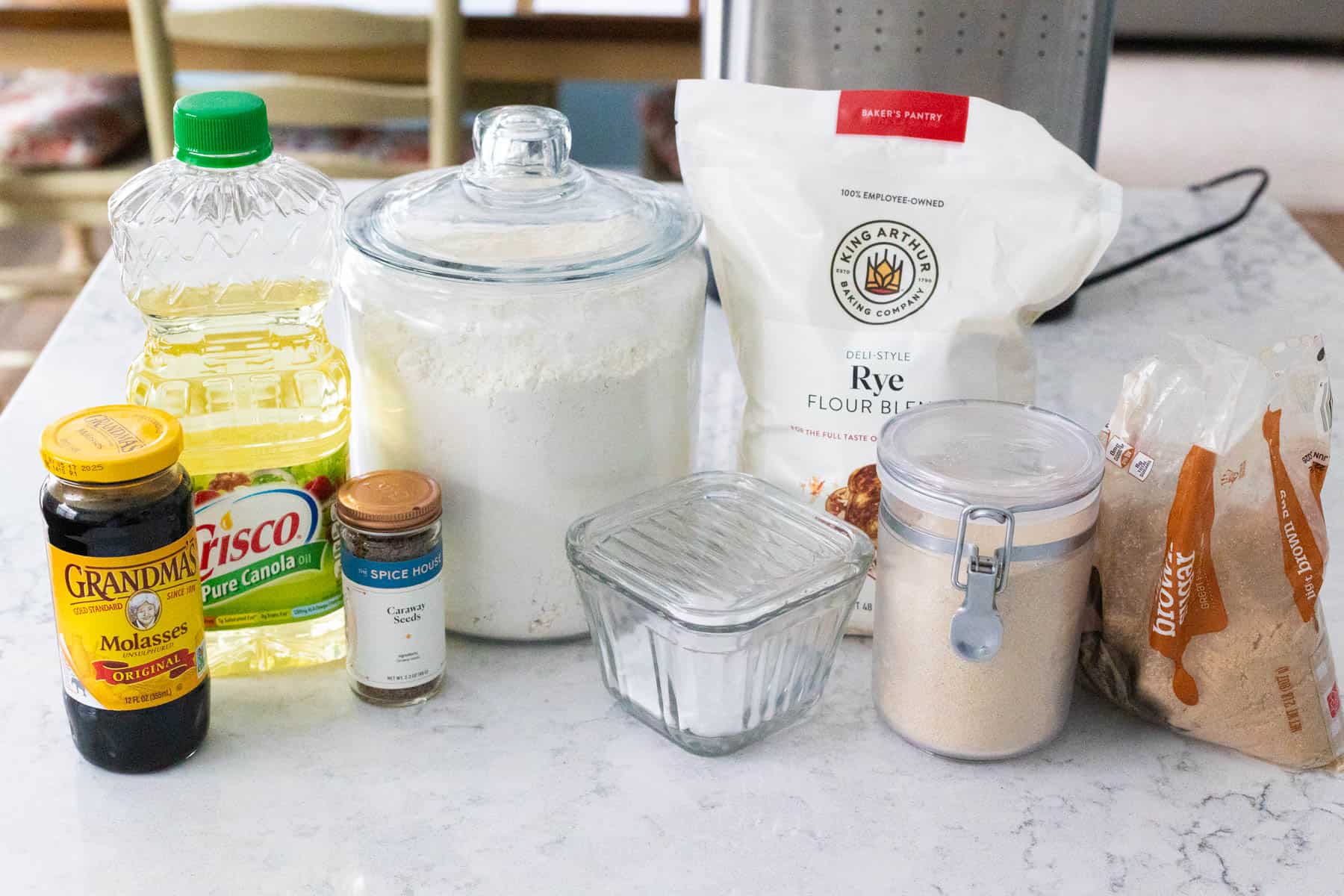 The ingredients to make rye bread in a bread maker are on the counter.