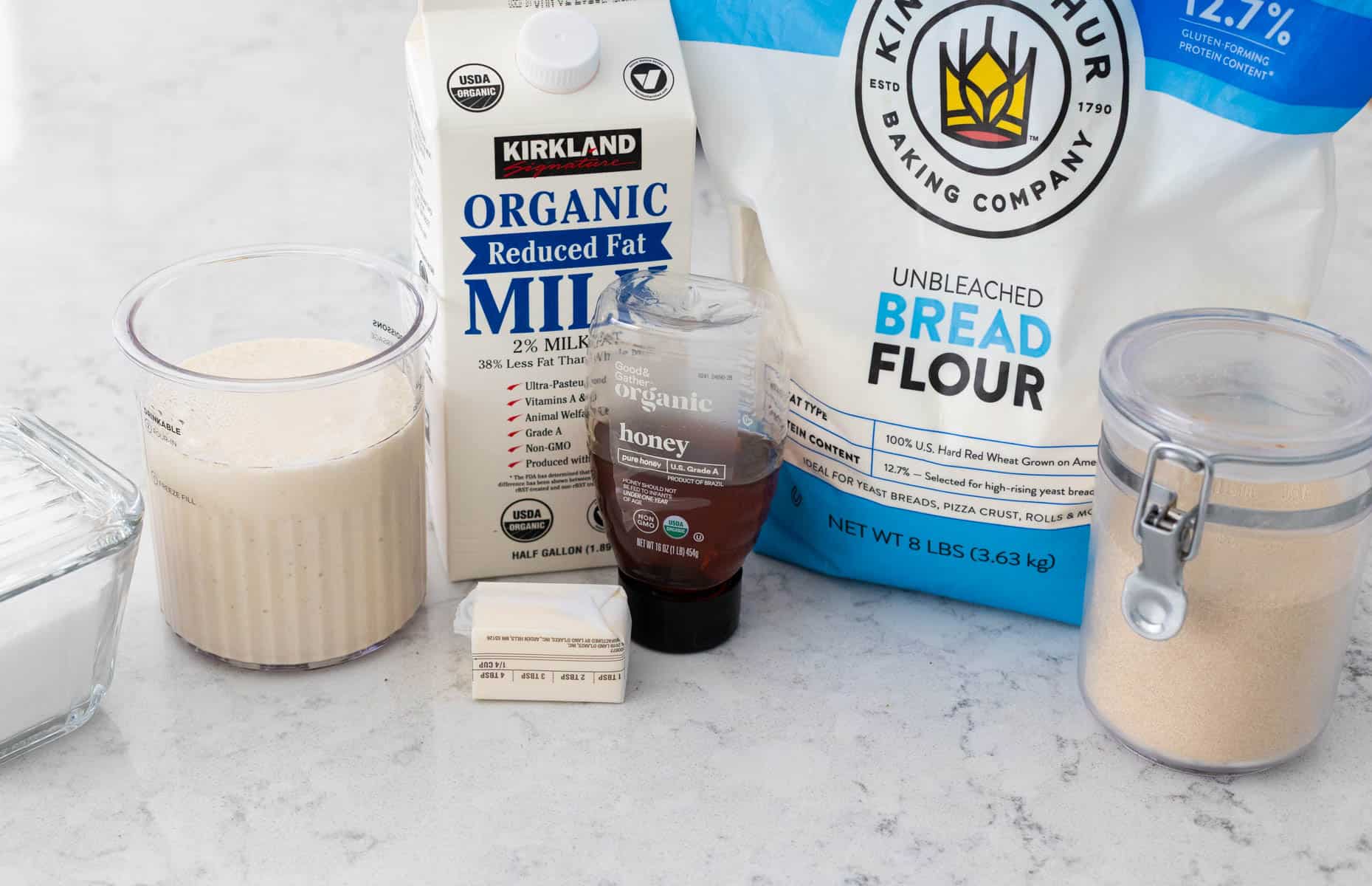 The ingredients to make a loaf of sourdough white bread in the bread machine are on the counter.