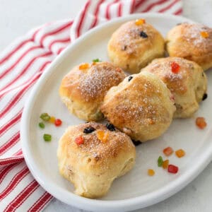 A white platter is filled with round stollen buns made with bread machine dough and candied fruits.