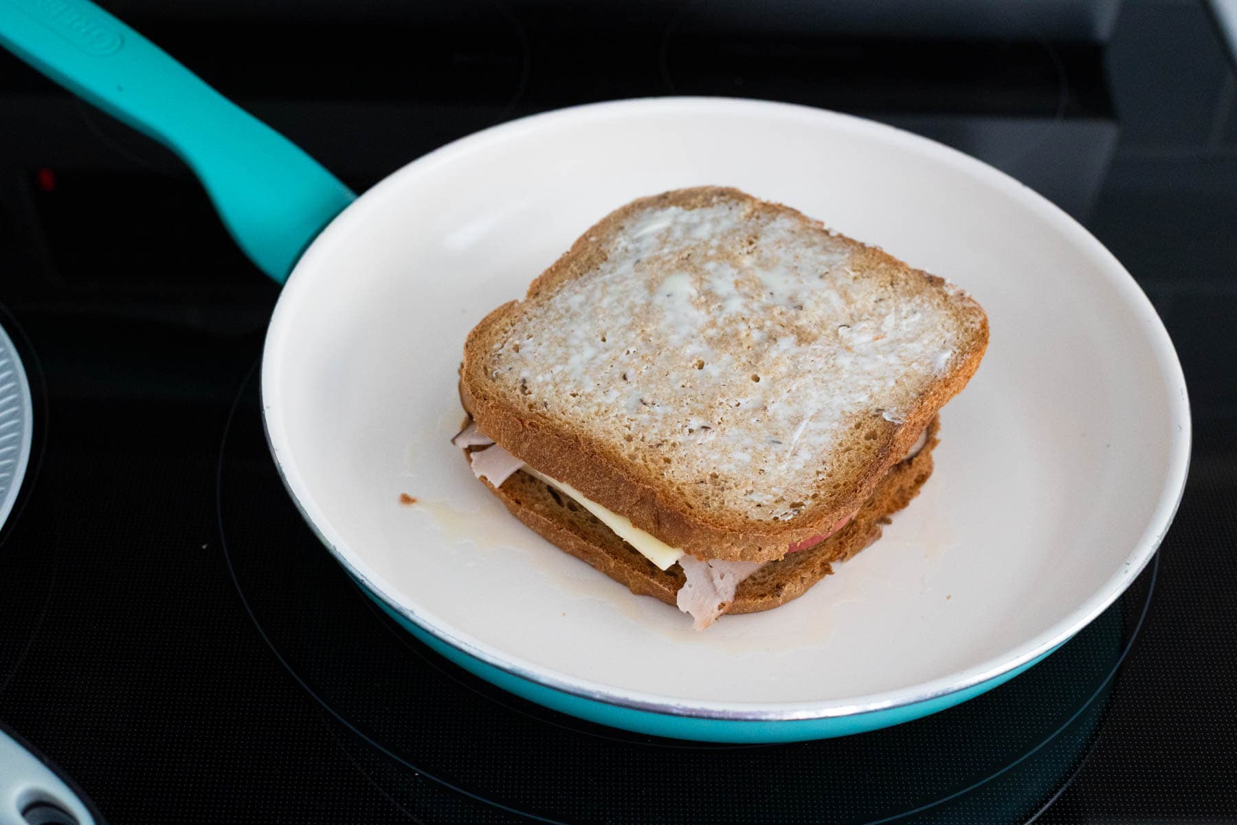 The turkey apple sandwich is in a small skillet with the buttered side facing up.