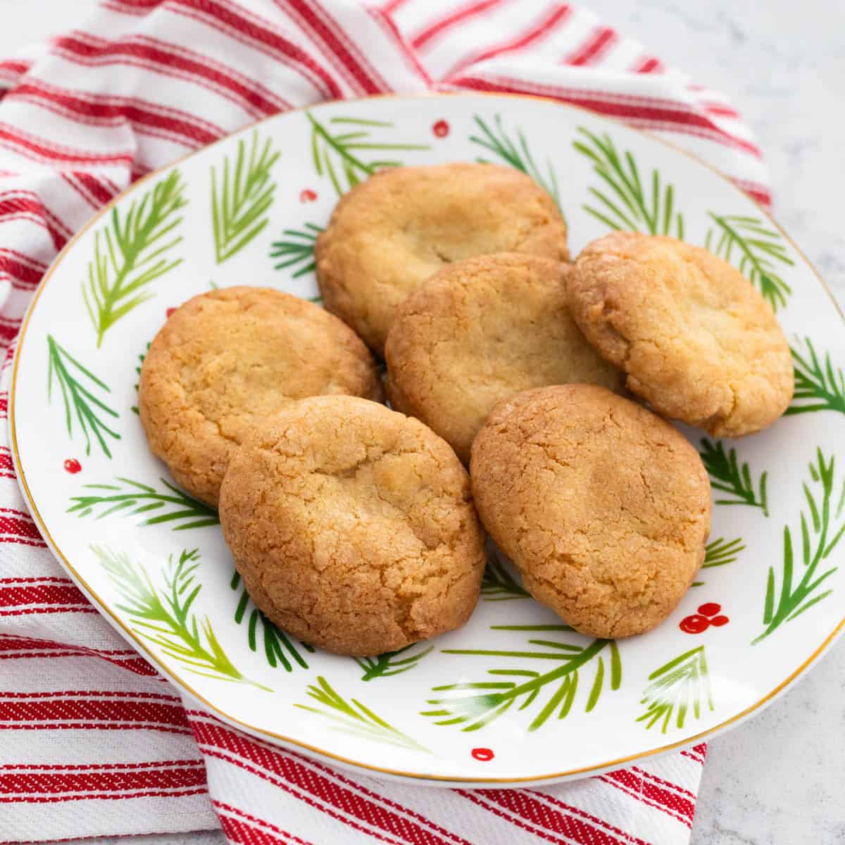 Une assiette de Noël remplie de biscuits à la vanille dorés.