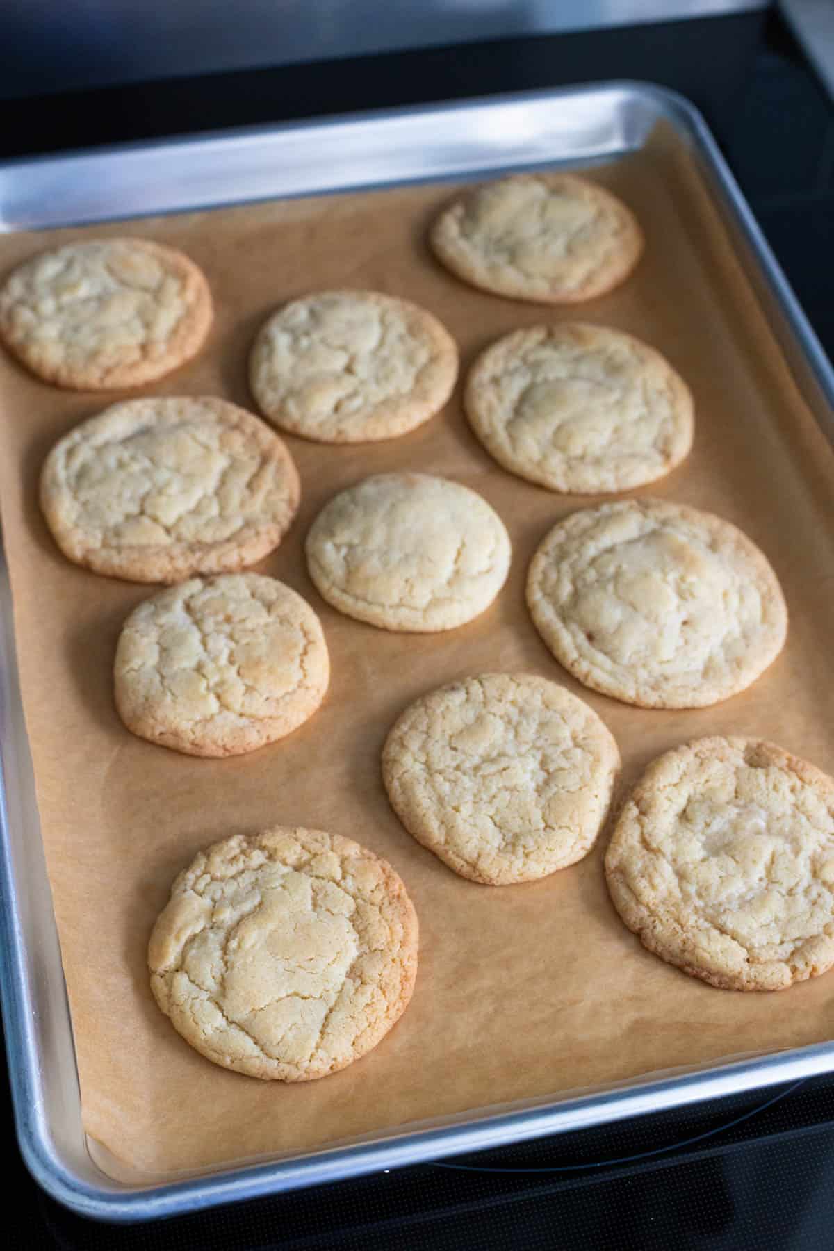 Un plateau de biscuits à la vanille fraîchement cuits refroidissant sur du papier sulfurisé.
