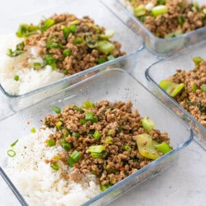 Four meal prep dishes are filled with beds of white rice topped with a ground pork and veggie mixture.
