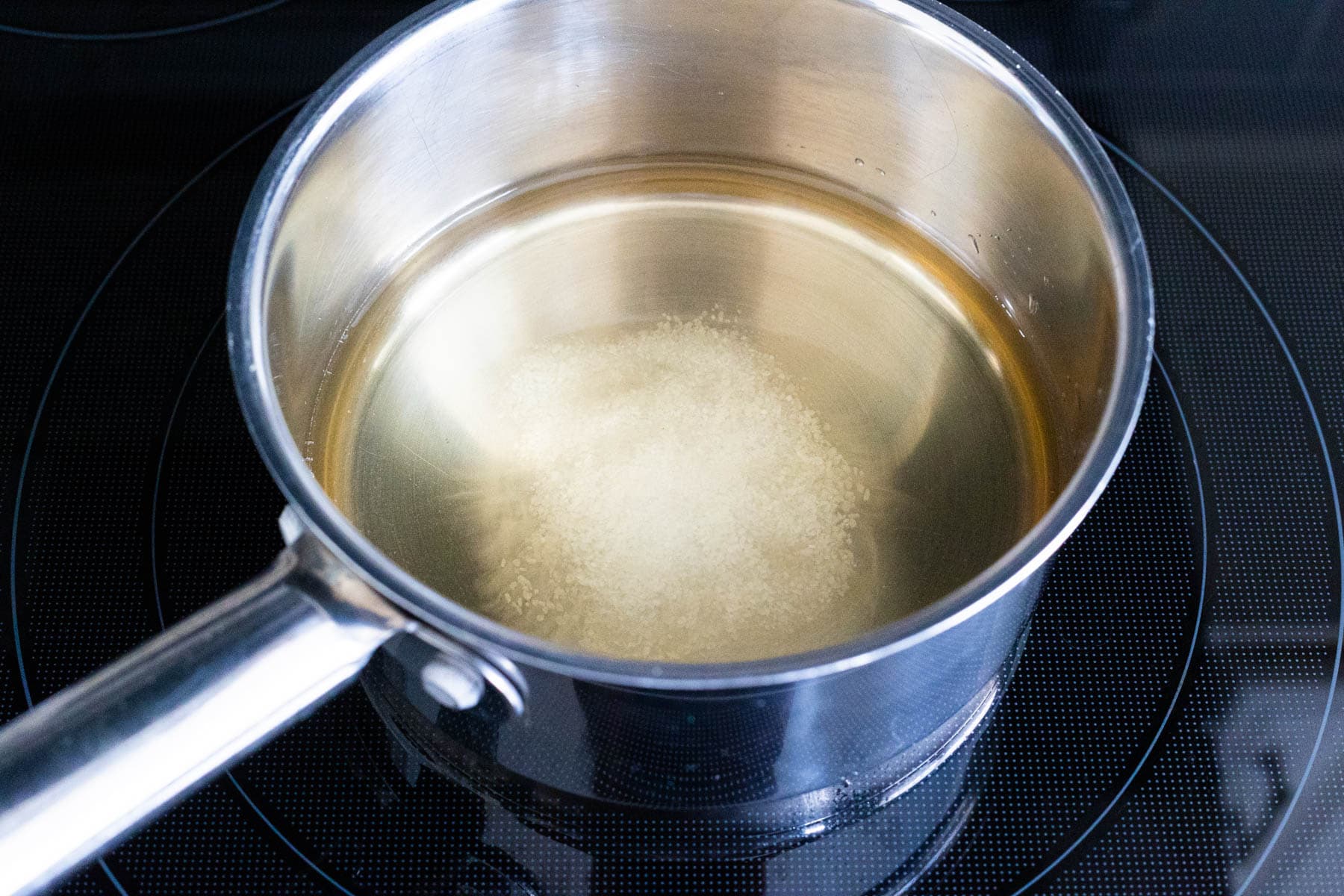 A small saucepan on a stovetop with vinegar, water, and sugar heating to make the pickling brine for Quick Pickled Vegetables.