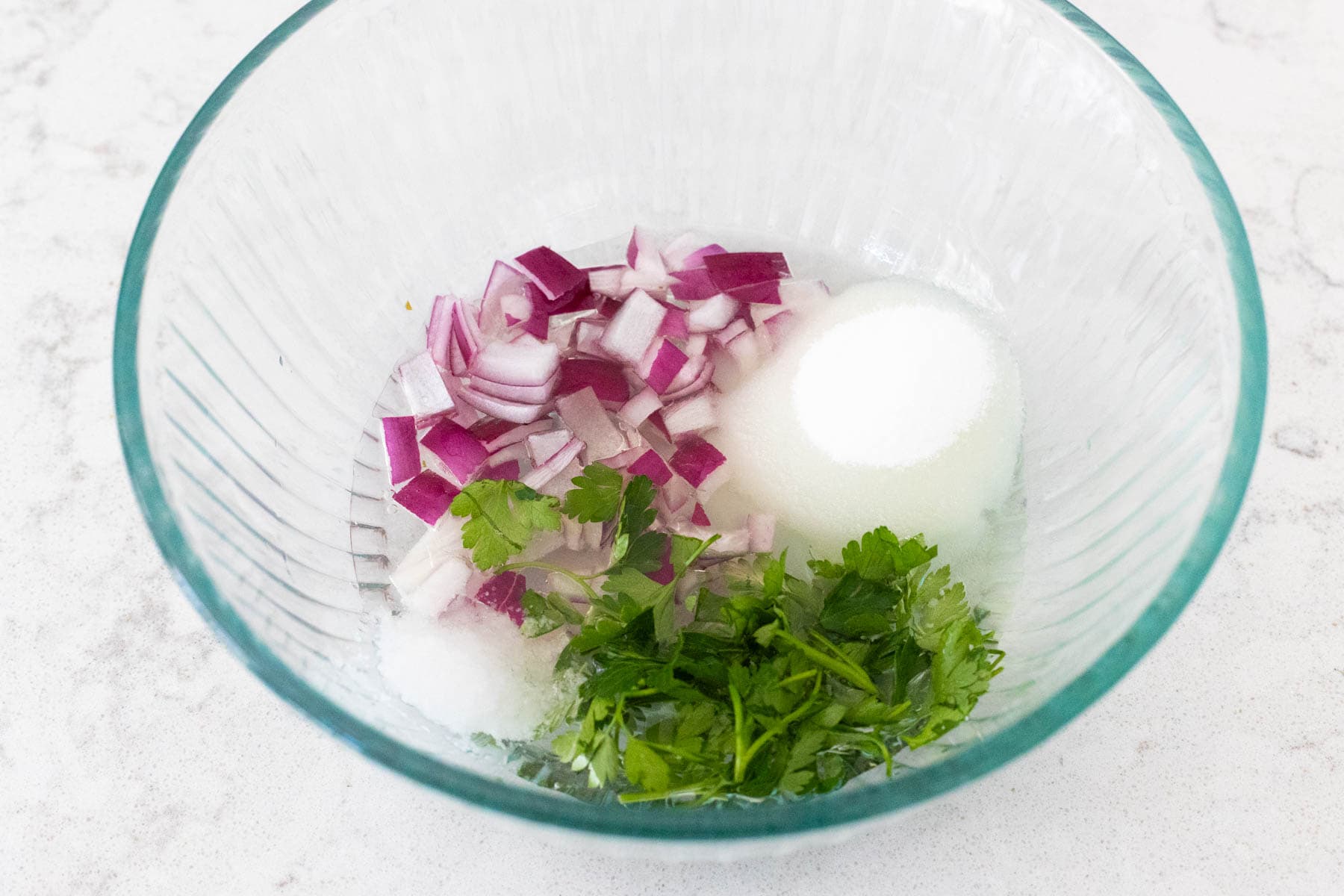 The chopped red onion, fresh parsley, and other ingredients are in a mixing bowl.