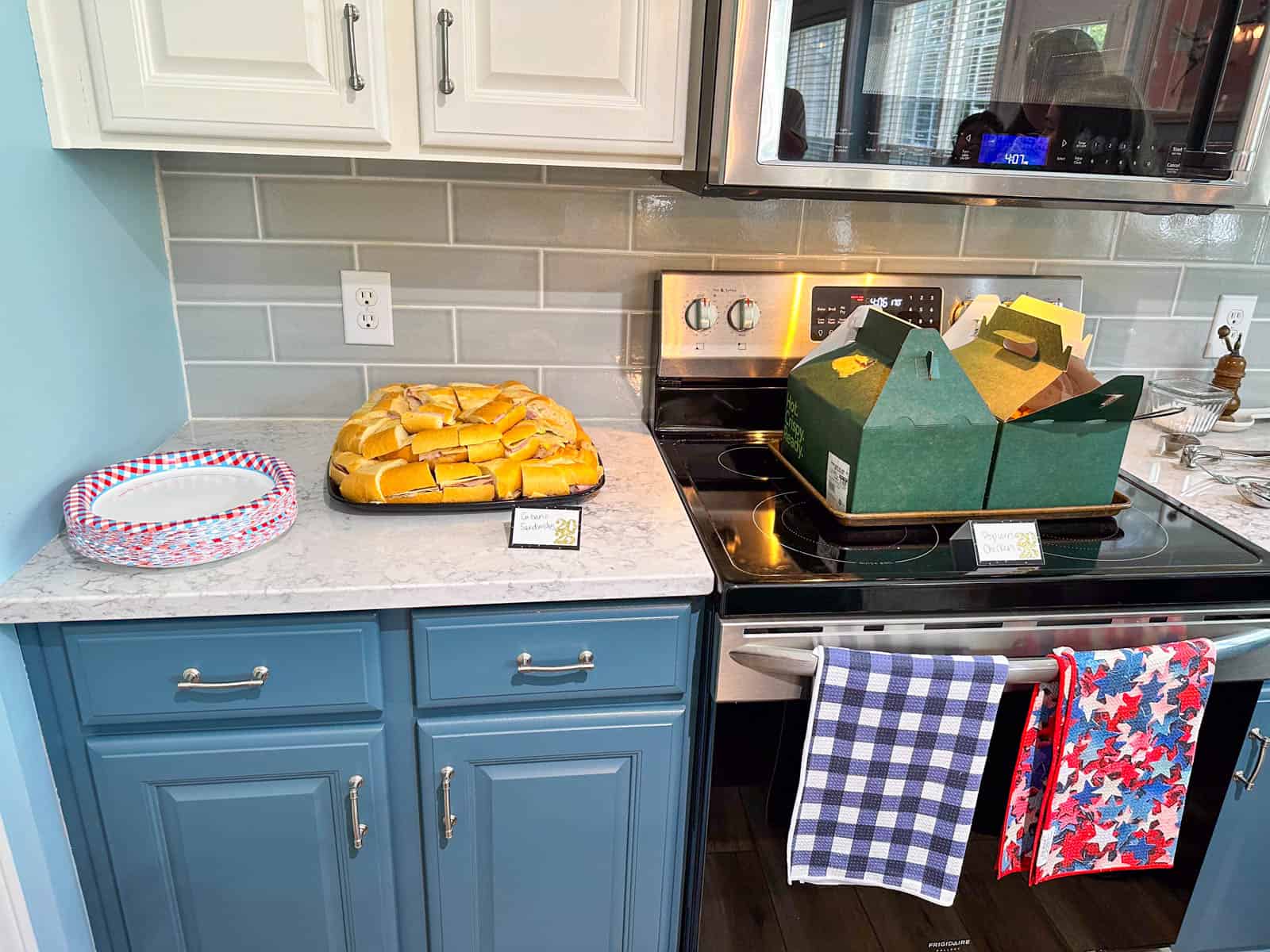 The sandwich platter and popcorn chicken containers are on the counter and stove top.