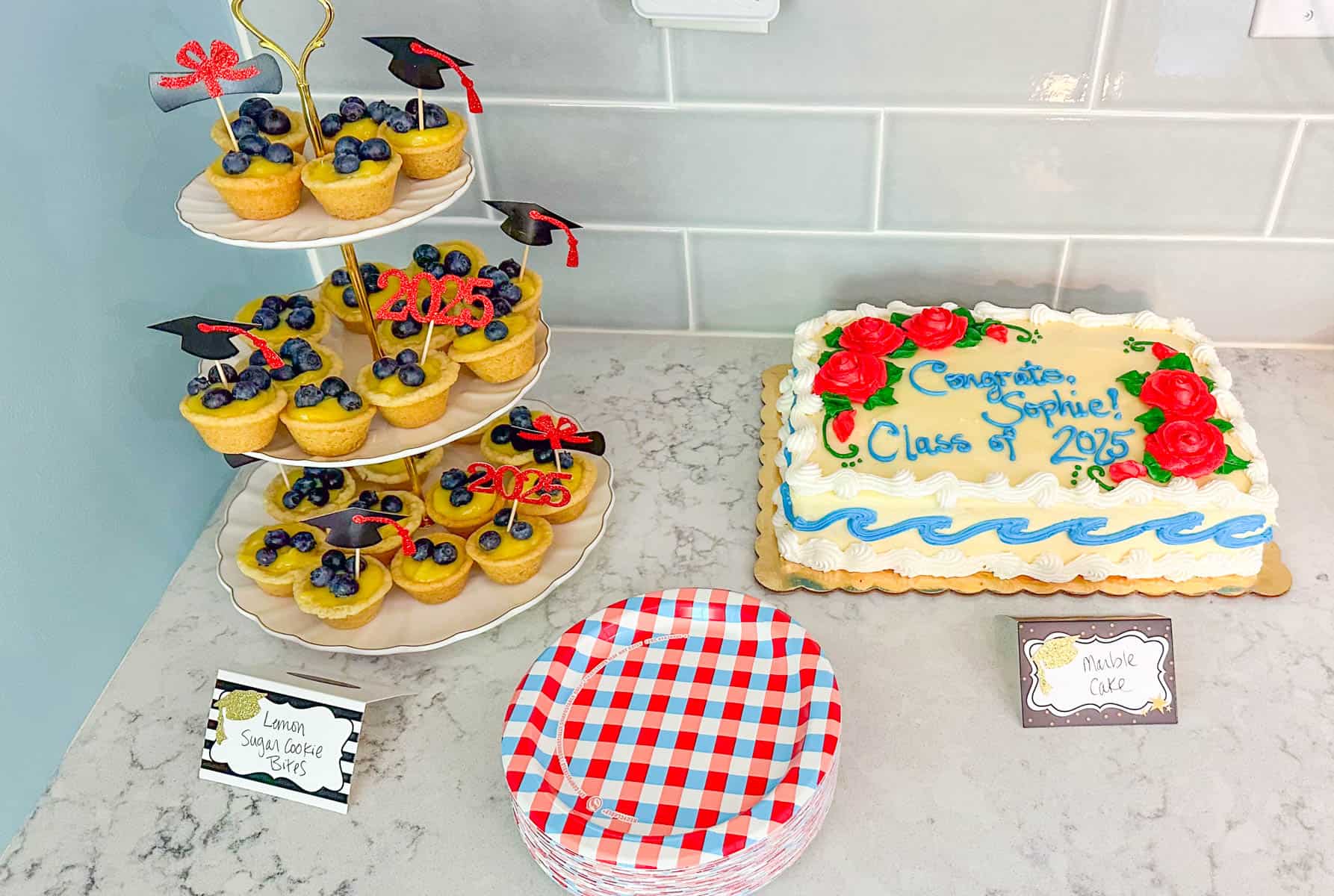 The tiered tower of treats sits next to a sheet cake and party plates.