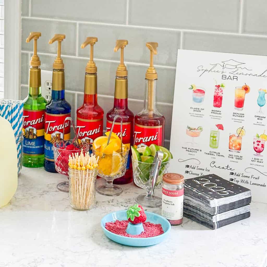 A DIY lemonade bar with flavored syrups and garnishes is set up in the kitchen.