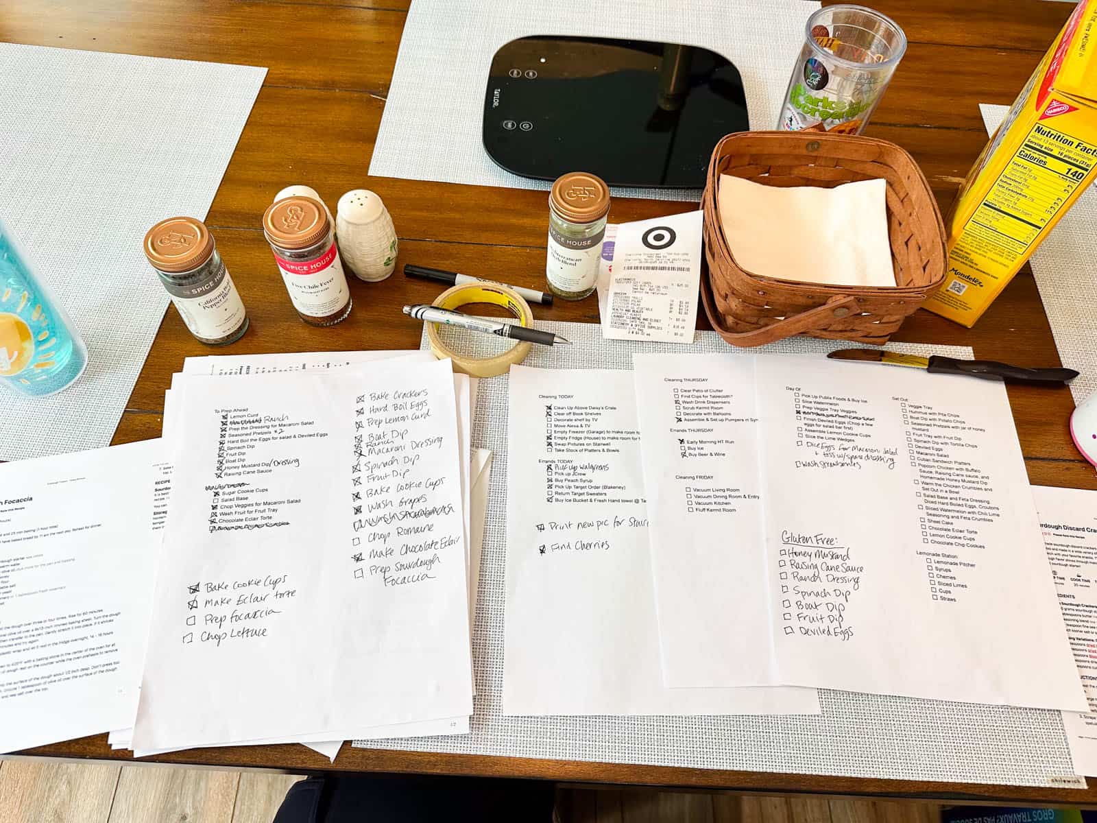 The print outs with checklists and handwritten notes on a messy kitchen table.