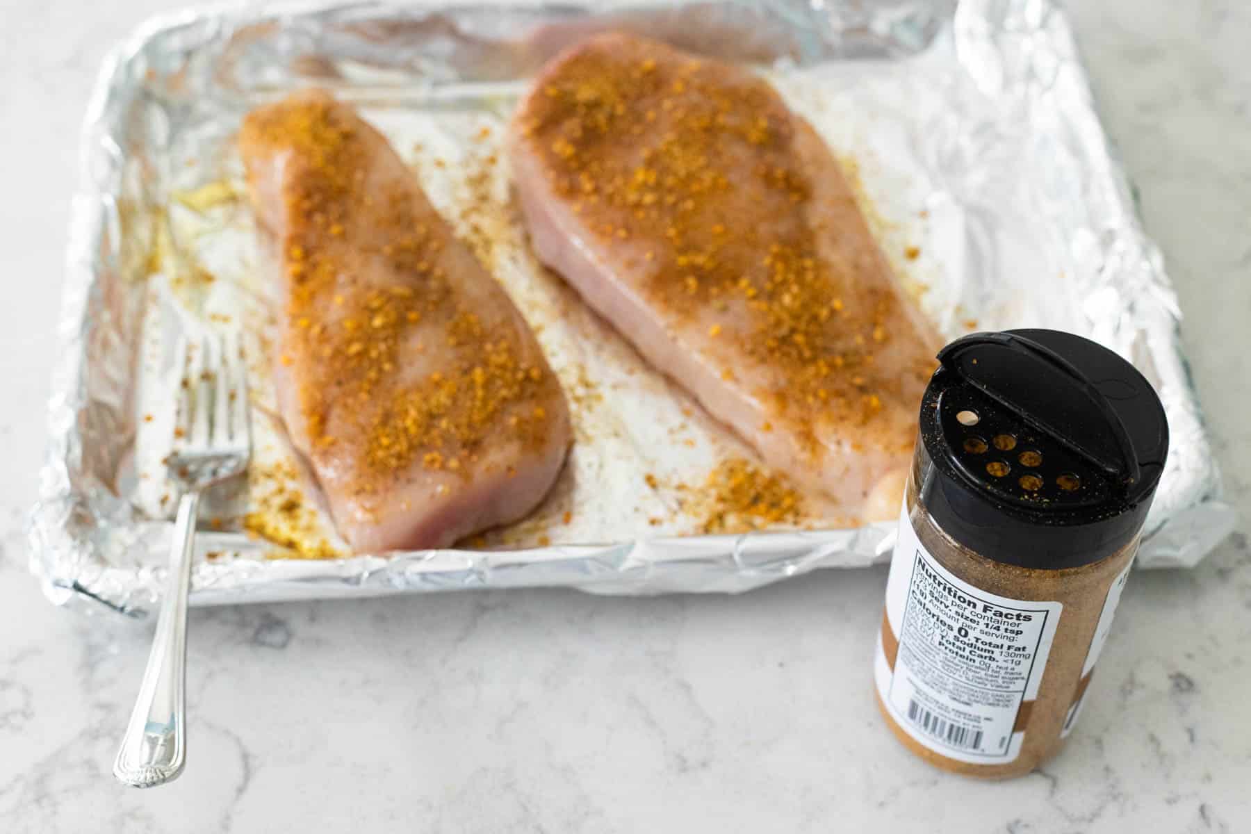 The chicken breasts have been coated in seasoning on both sides.