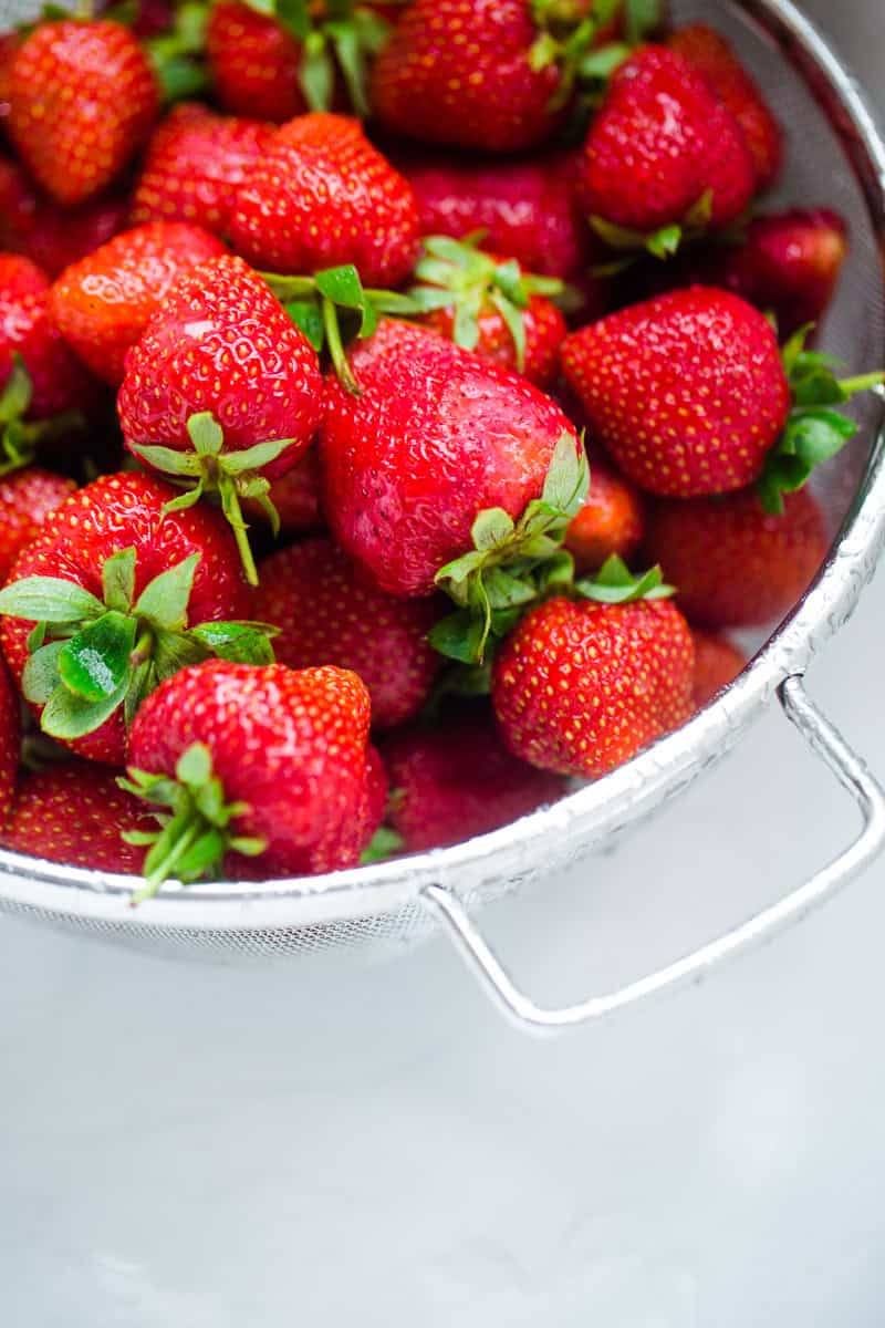 The fresh strawberries are in a collander.