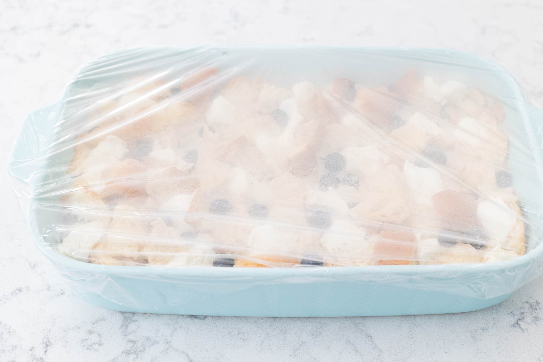 The baking dish is covered in plastic wrap.