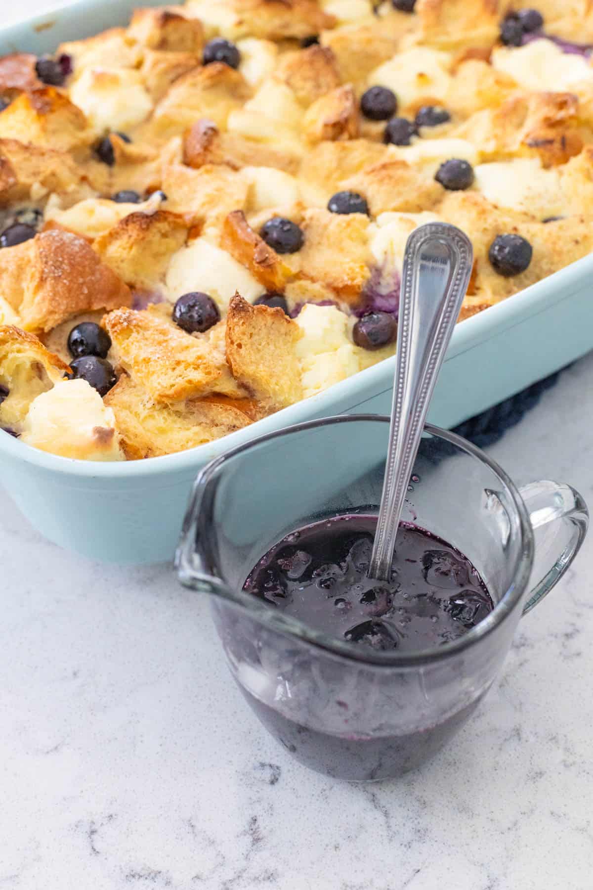 The blueberry syrup sits next to a breakfast casserole.