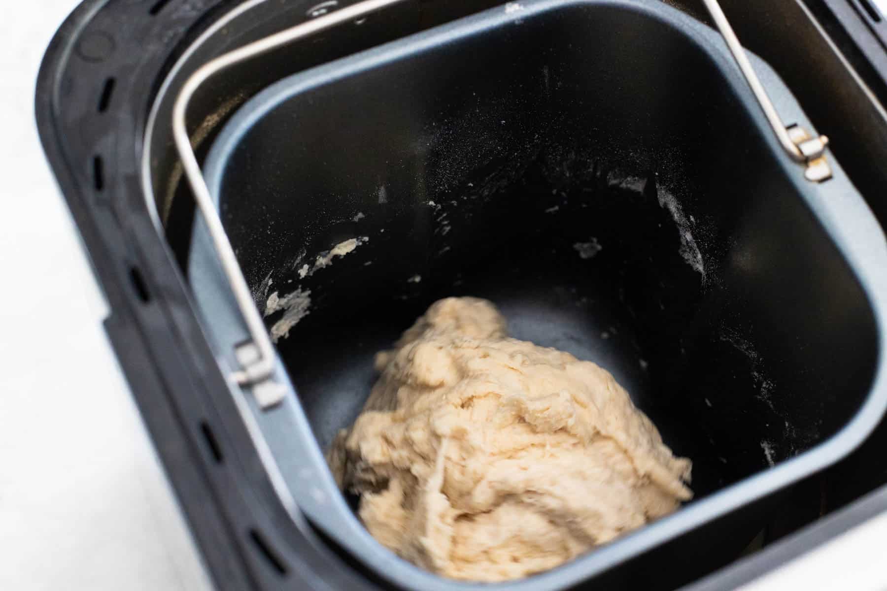 The ingredients have been mixed together inside the bread machine. The dough looks a little bit dry and shaggy.