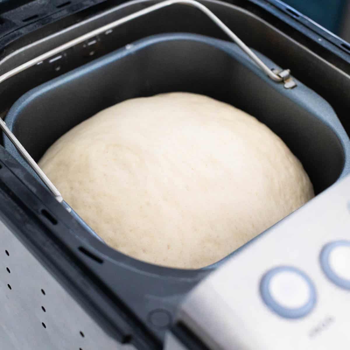 The risen dough is sitting in the bread pan inside the bread machine.