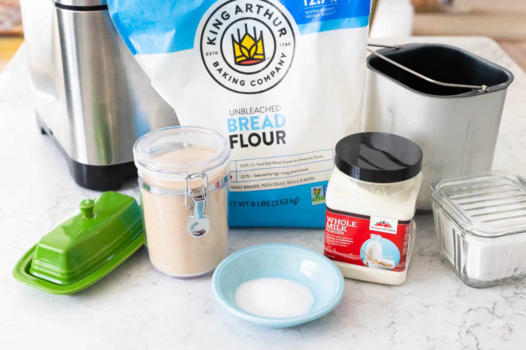 The ingredients to make homemade dough in the bread machine are sitting on the kitchen counter.