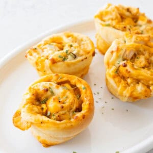 A white serving platter is filled with homemade buffalo chicken rolls.