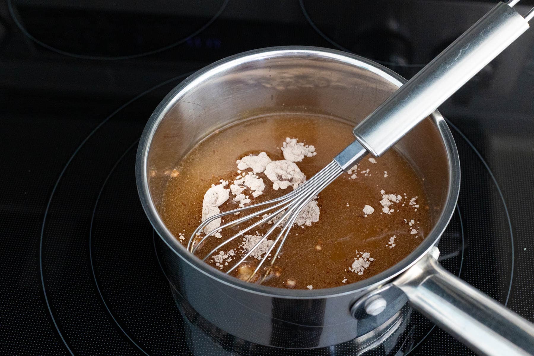 The au jus dipping sauce is simmering in a saucepan. 
