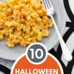 A gray plate is filled with orange Halloween mac and cheese and rests on a spider web placemat.