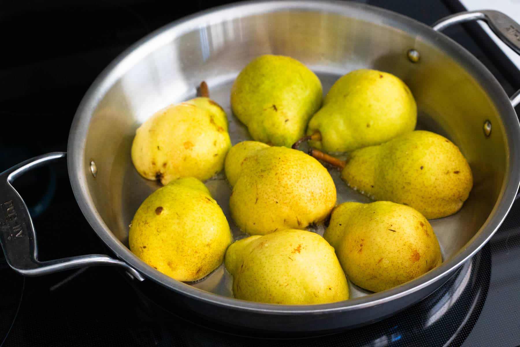 The pear halves are faced down in a large skillet.