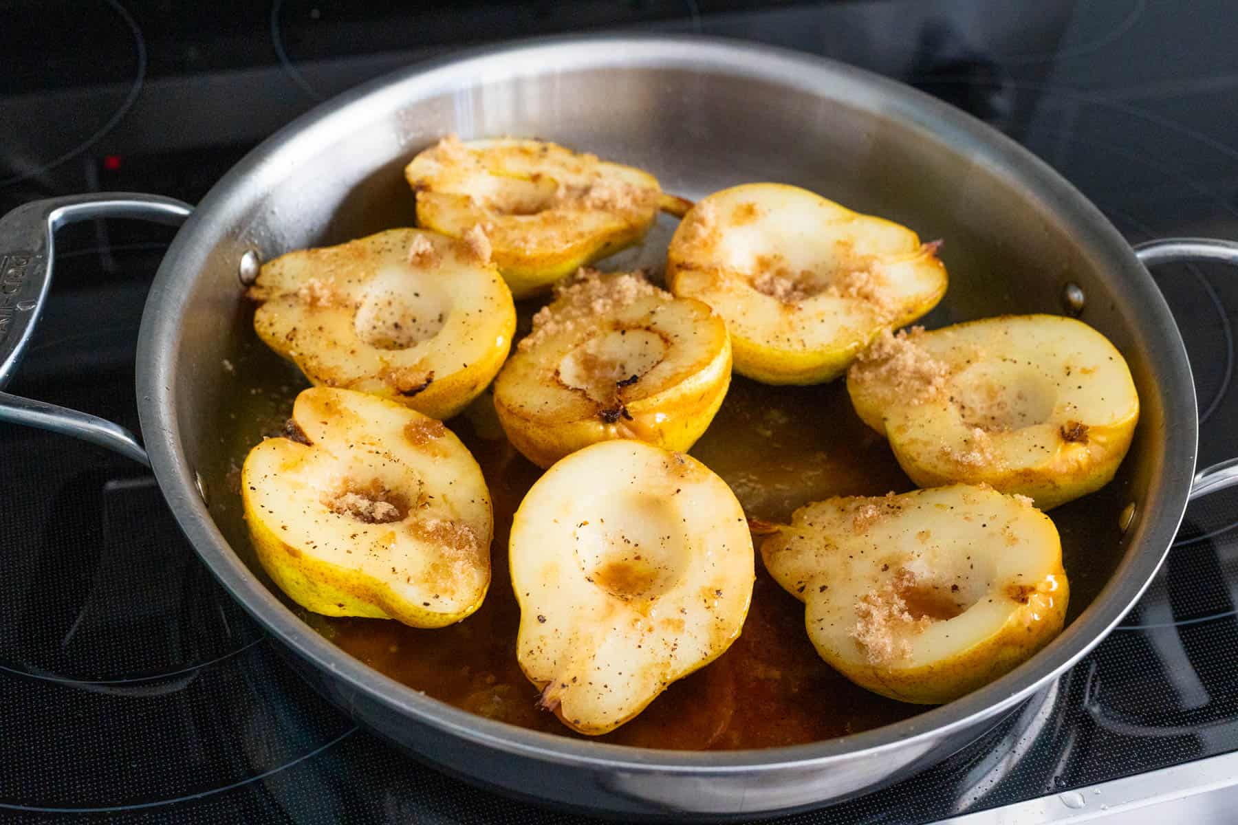 The roasted pears have just come out of the oven and are cooling in the skillet on the stovetop.