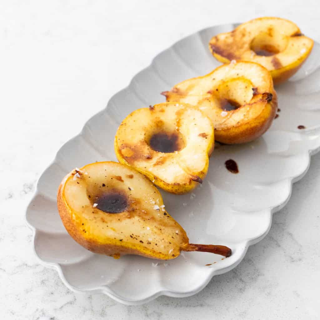 The serving platter has 4 roasted pear halves lined up for dinner.