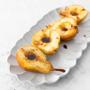 The serving platter has 4 roasted pear halves lined up for dinner.
