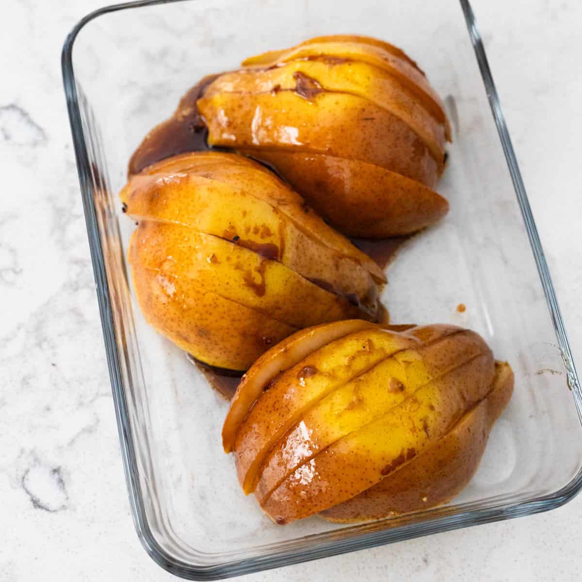 The sliced pear halves have been lined up in a storage dish, ready to go in the fridge.