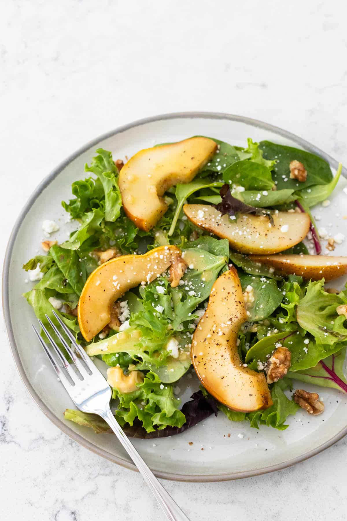 The roasted pear salad has been assembled on a plate.